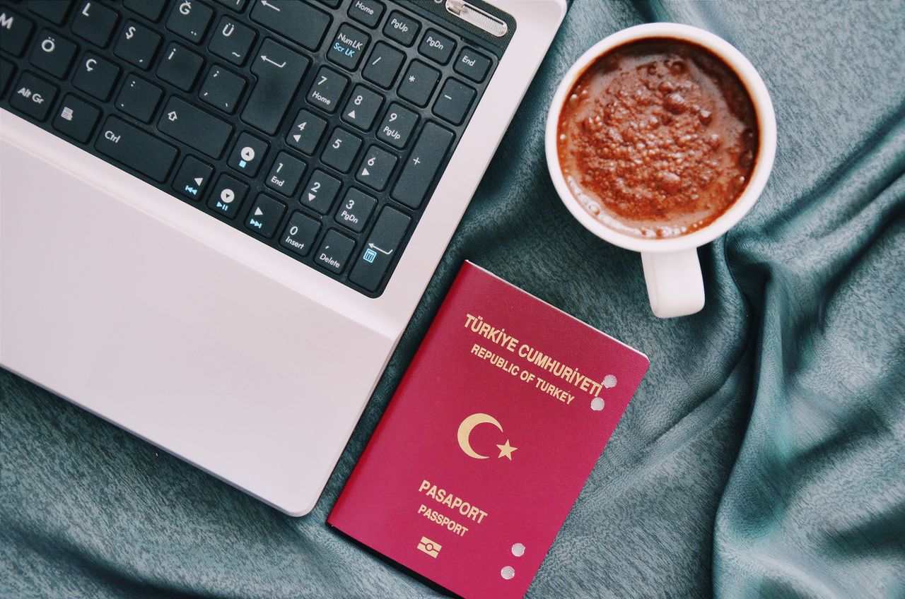 Services A Turkish passport beside a coffee cup and laptop, symbolizing travel and technology.