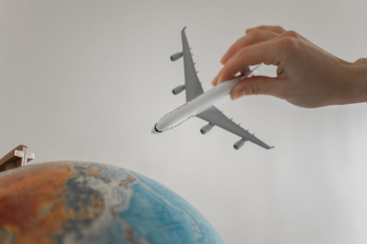 Services A hand holds a toy airplane above a globe, symbolizing travel and exploration.